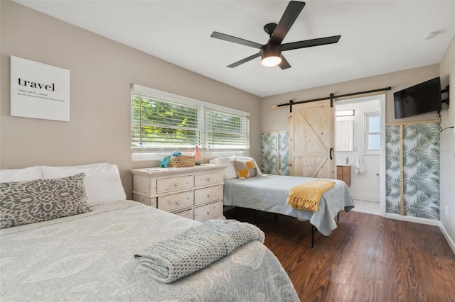 bedroom with a barn door, wood finished floors, a ceiling fan, and baseboards