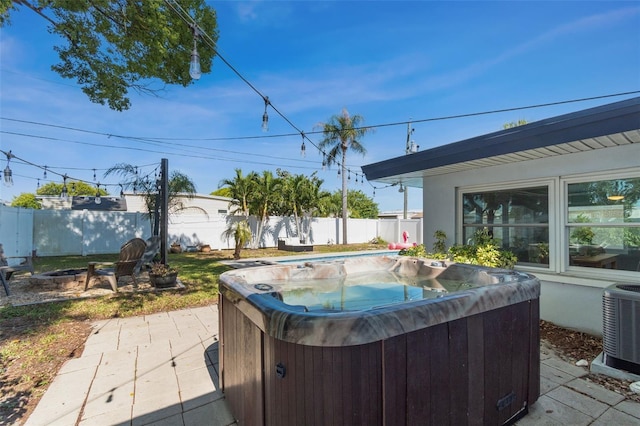 view of patio featuring a hot tub, an outdoor fire pit, and cooling unit