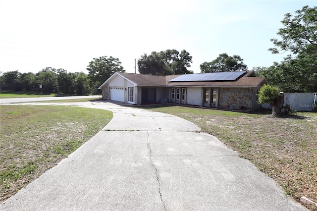 8209 Chaucer Dr, Weeki Wachee, FL 34607 - view of front of house featuring a front lawn, solar panels, an attached garage, and driveway