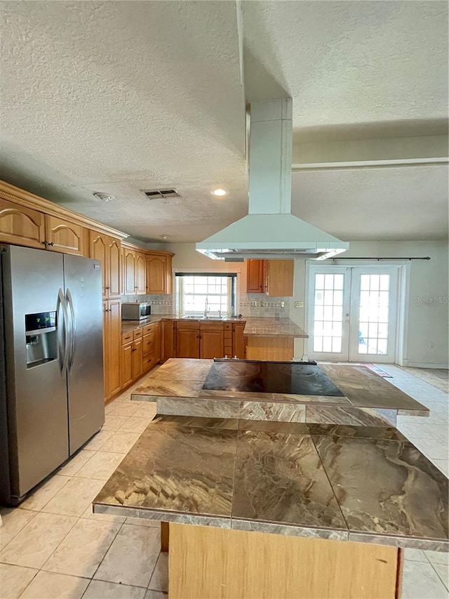 8209 Chaucer Dr, Weeki Wachee, FL 34607 - kitchen featuring appliances with stainless steel finishes, island range hood, a textured ceiling, backsplash, and french doors
