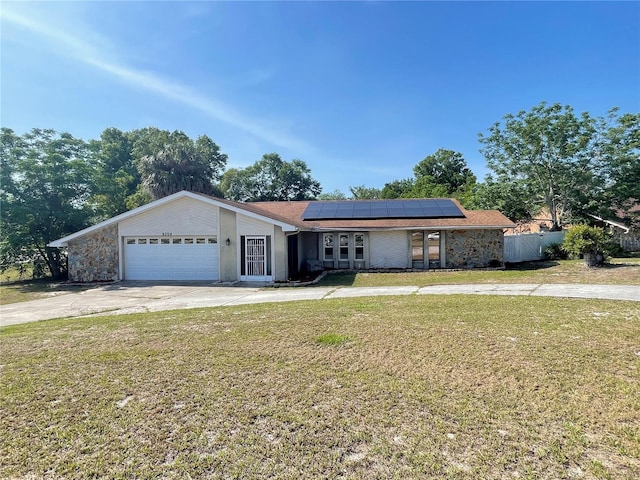 8209 Chaucer Dr, Weeki Wachee, FL 34607 - view of front facade featuring roof mounted solar panels, concrete driveway, a garage, and stone siding