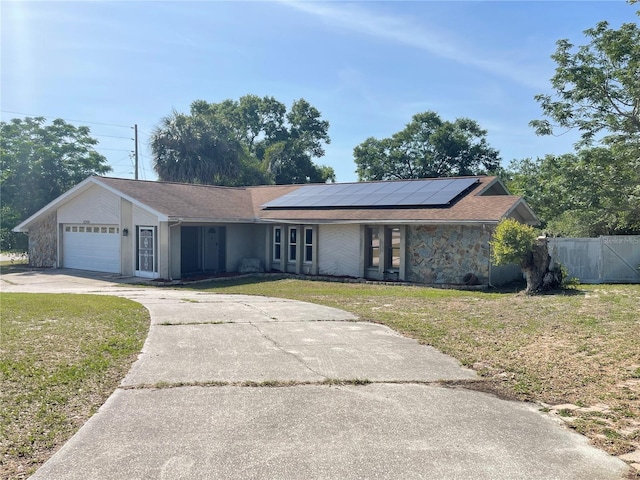 8209 Chaucer Dr, Weeki Wachee, FL 34607 - view of front of property featuring driveway, solar panels, an attached garage, and stone siding