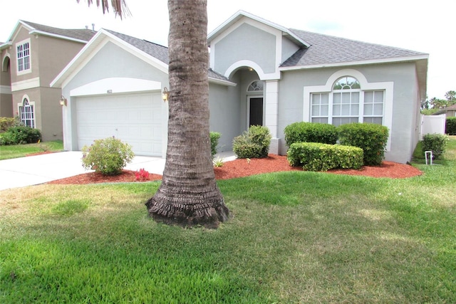 view of front of property featuring roof with shingles, a front yard, concrete driveway, stucco siding, and an attached garage