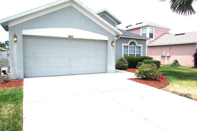 view of front of property featuring stucco siding, a garage, and driveway