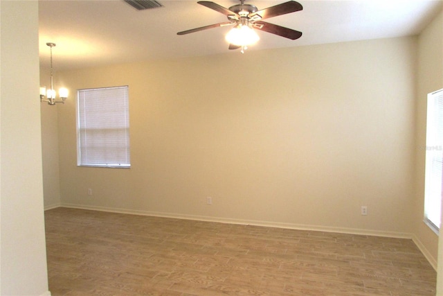 unfurnished room featuring light wood-style floors, a chandelier, ceiling fan, and baseboards