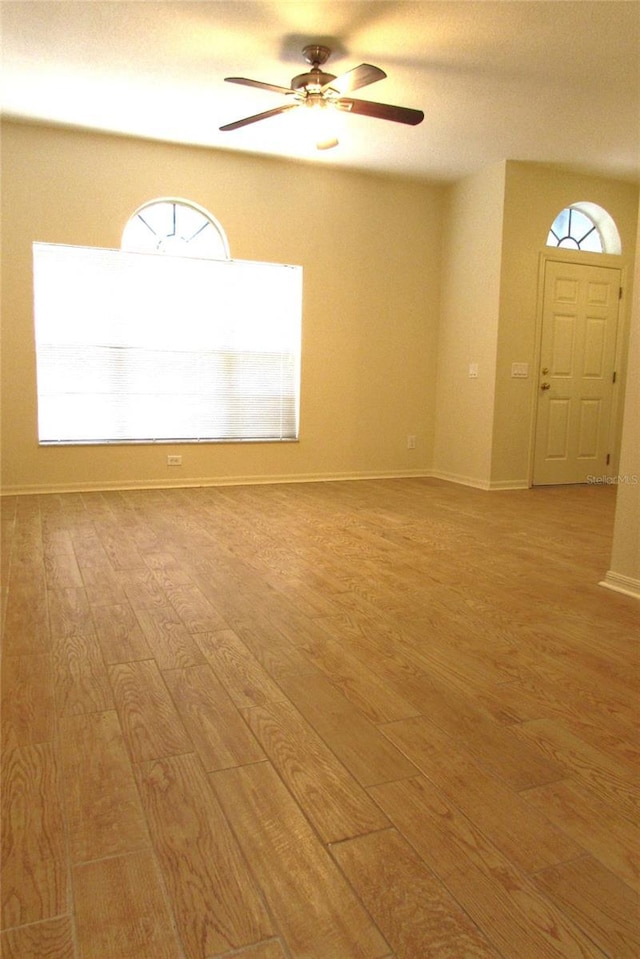 spare room featuring light wood-style floors, ceiling fan, and plenty of natural light