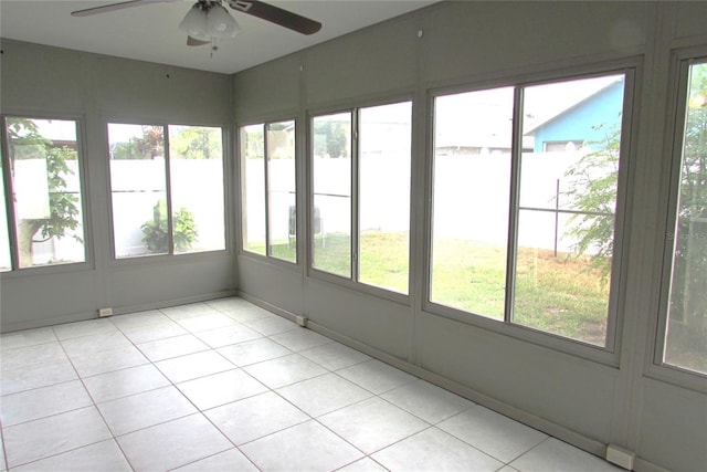unfurnished sunroom with a ceiling fan, plenty of natural light, and tile patterned floors