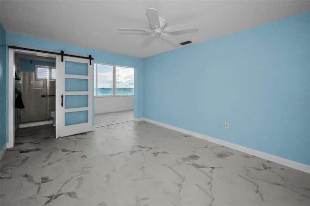 unfurnished bedroom featuring baseboards, marble finish floors, and a barn door