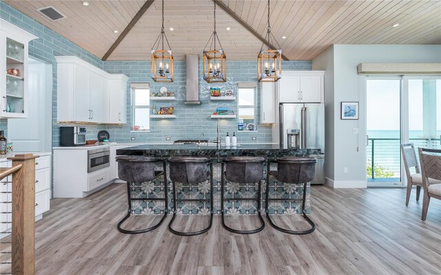 4620 Oro Pesos Ln, Captiva, FL 33924 - kitchen featuring wooden ceiling, wall chimney exhaust hood, stainless steel appliances, light wood-type flooring, and white cabinetry