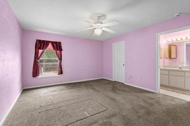 unfurnished bedroom with light colored carpet, baseboards, a sink, connected bathroom, and a ceiling fan