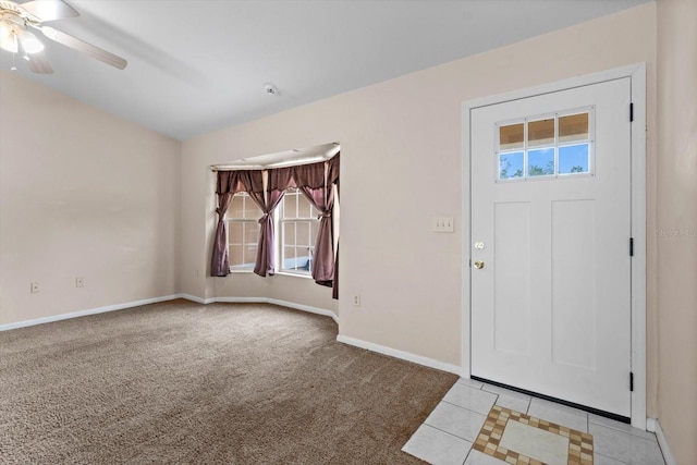 entryway with a ceiling fan, baseboards, light tile patterned flooring, light carpet, and lofted ceiling