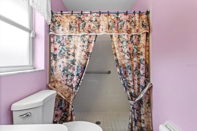 bathroom with tiled shower and toilet