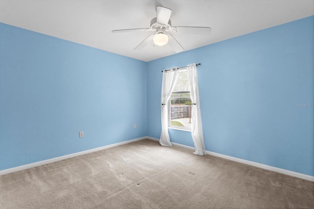 empty room featuring carpet flooring, a ceiling fan, and baseboards