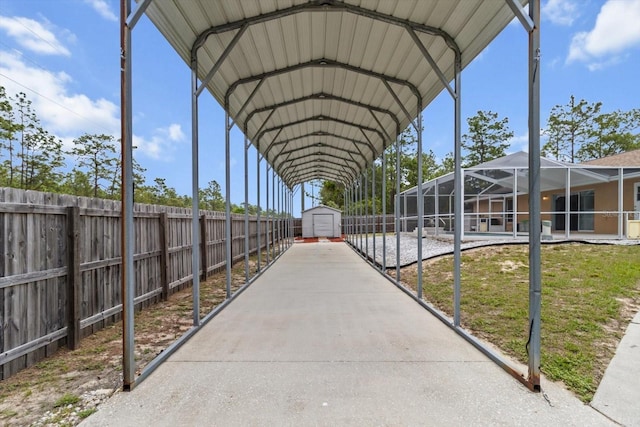 view of parking with fence, a detached carport, and a storage unit