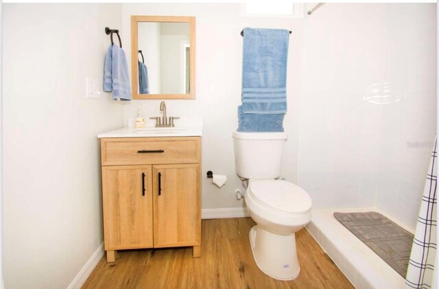 1933 Oxnard Ct, Tampa, FL 33612 - full bathroom with wood finished floors, a tile shower, toilet, vanity, and baseboards