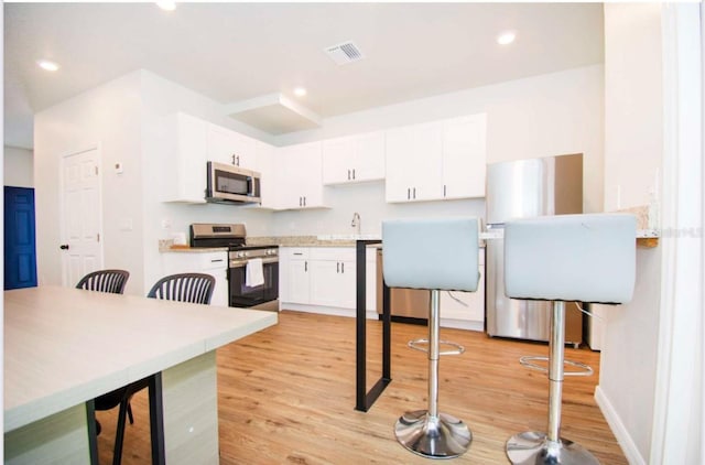 1933 Oxnard Ct, Tampa, FL 33612 - kitchen with appliances with stainless steel finishes, white cabinets, light wood-type flooring, light countertops, and recessed lighting