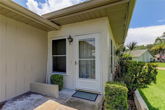 view of exterior entry featuring a patio area and a yard