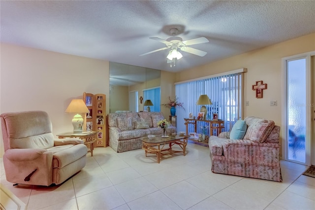 living room with ceiling fan, light tile patterned floors, and a textured ceiling