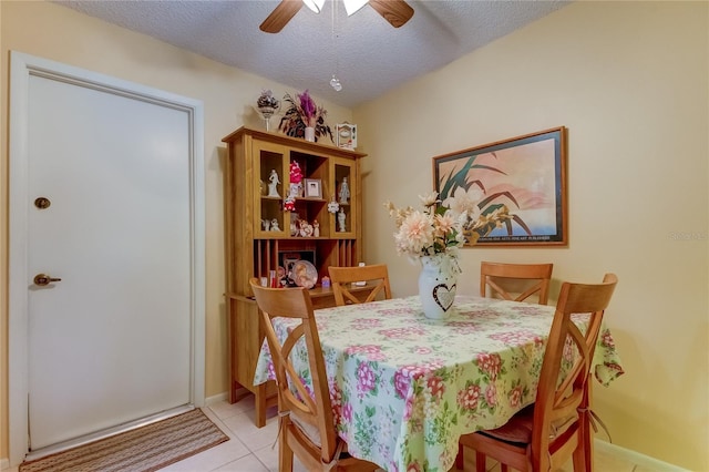 dining room with a ceiling fan, a textured ceiling, light tile patterned floors, and baseboards