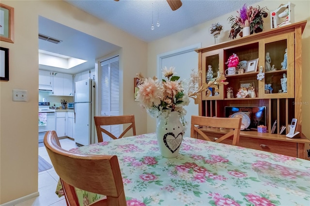 dining space with a ceiling fan and light tile patterned floors