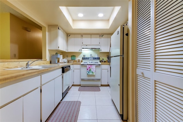 kitchen featuring white appliances, a sink, light countertops, a raised ceiling, and under cabinet range hood