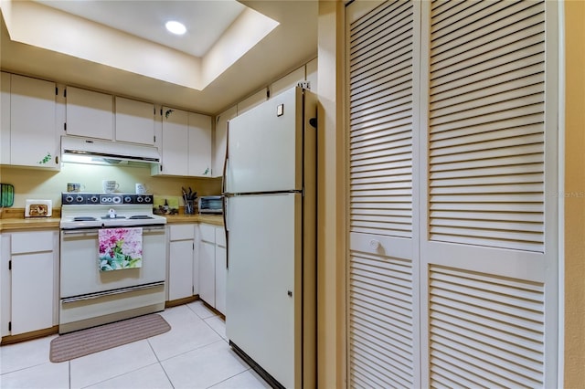 kitchen with white appliances, range hood, light countertops, light tile patterned floors, and white cabinets