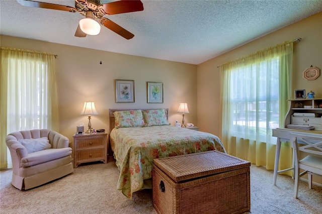 bedroom featuring carpet flooring, multiple windows, a textured ceiling, and a ceiling fan
