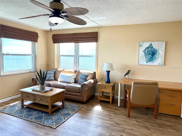living room featuring a ceiling fan, wood finished floors, a textured ceiling, and baseboards