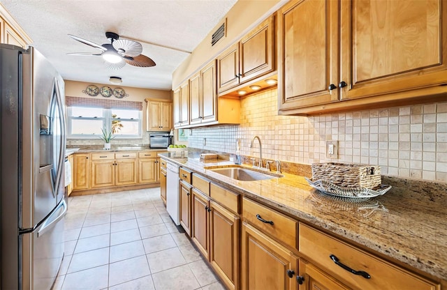 kitchen featuring stainless steel refrigerator with ice dispenser, a sink, dishwasher, ceiling fan, and decorative backsplash