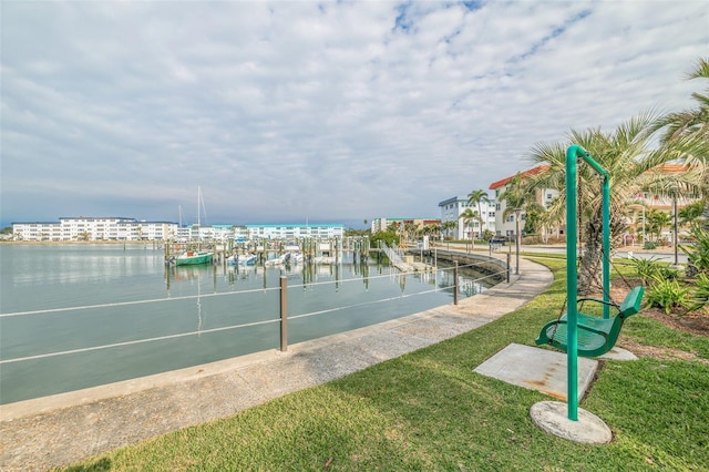 view of home's community with a boat dock, a water view, and a yard