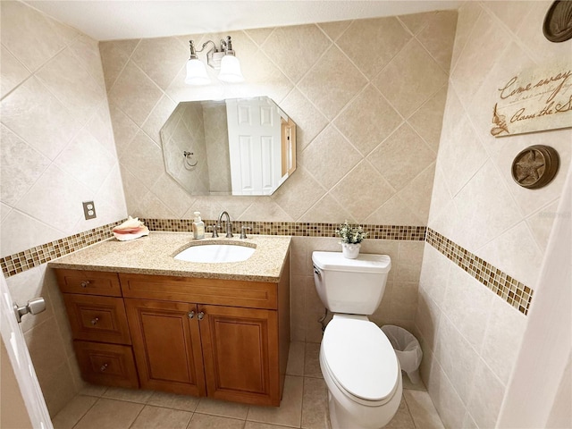 bathroom with tile walls, tile patterned floors, toilet, and vanity