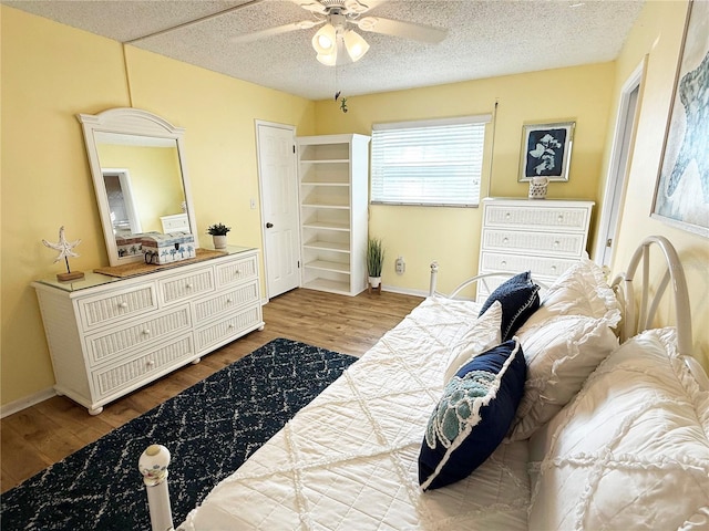 bedroom with wood finished floors, baseboards, a textured ceiling, and ceiling fan