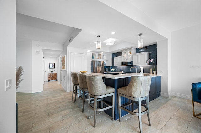 1325 Snell Isle Blvd NE Unit 810, Saint Petersburg, FL 33704 - kitchen featuring a peninsula, appliances with stainless steel finishes, light countertops, a breakfast bar area, and baseboards