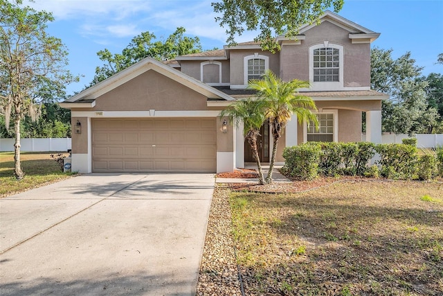 traditional-style house with stucco siding, fence, an attached garage, and concrete driveway