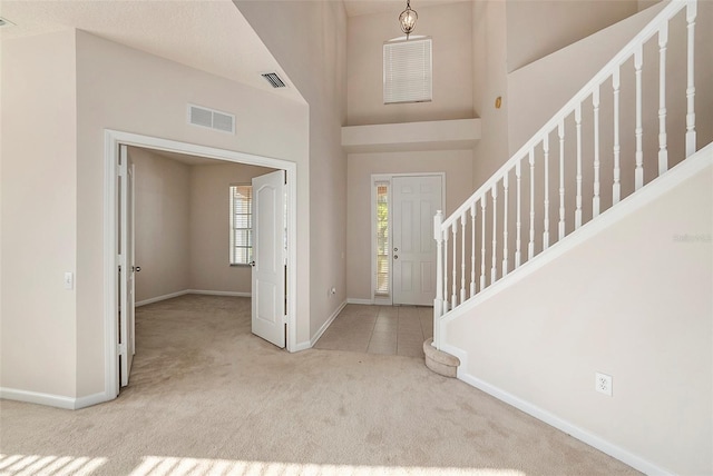 carpeted foyer entrance featuring baseboards and stairway