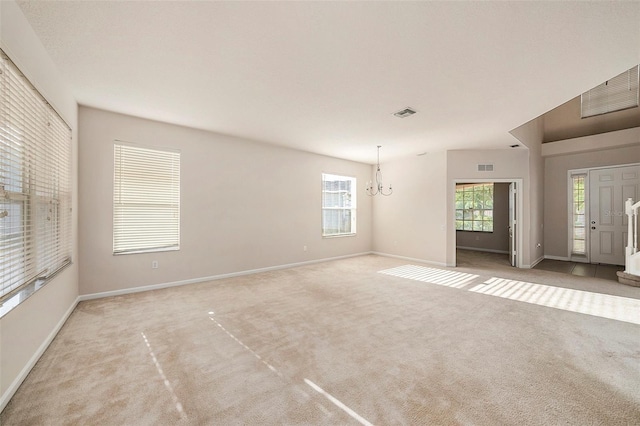 unfurnished living room featuring carpet, a chandelier, healthy amount of natural light, and baseboards