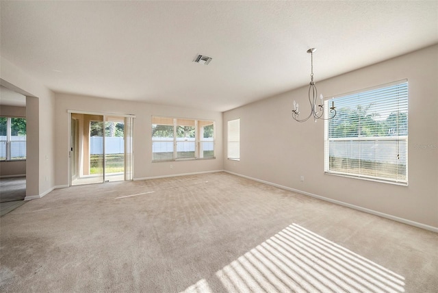 spare room with light colored carpet, a chandelier, and baseboards