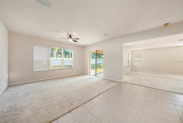 unfurnished room featuring light carpet, a ceiling fan, baseboards, light tile patterned flooring, and a smoke detector