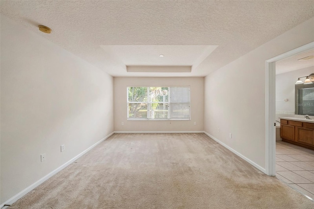 unfurnished room with light carpet, a smoke detector, a textured ceiling, a sink, and baseboards