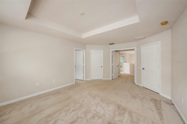 unfurnished bedroom featuring carpet flooring, a raised ceiling, baseboards, and a textured ceiling