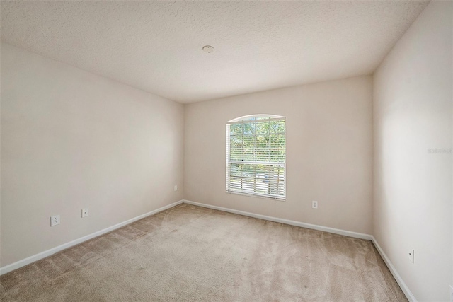 carpeted empty room with baseboards and a textured ceiling