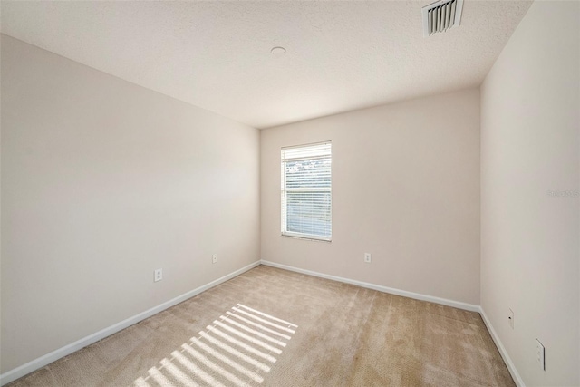 spare room featuring light carpet and baseboards