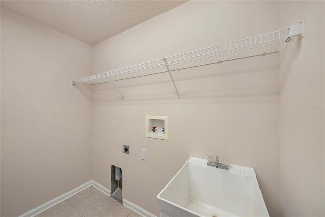 laundry area with hookup for an electric dryer, baseboards, washer hookup, light tile patterned flooring, and a textured ceiling