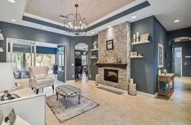 21513 Belvedere Ln, Estero, FL 33928 - tiled living area featuring arched walkways, a tray ceiling, recessed lighting, a chandelier, and a fireplace