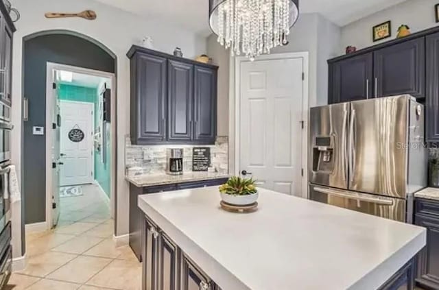 21513 Belvedere Ln, Estero, FL 33928 - kitchen with stainless steel refrigerator with ice dispenser, light countertops, a kitchen island, arched walkways, and a chandelier