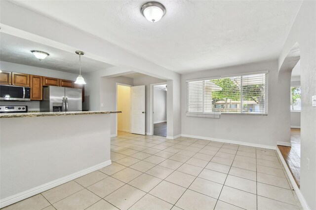 5010 8th Ave N, Saint Petersburg, FL 33710 - kitchen with appliances with stainless steel finishes, brown cabinets, light tile patterned flooring, arched walkways, and pendant lighting