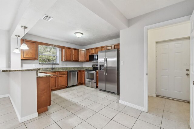 5010 8th Ave N, Saint Petersburg, FL 33710 - kitchen featuring appliances with stainless steel finishes, a peninsula, brown cabinetry, and baseboards