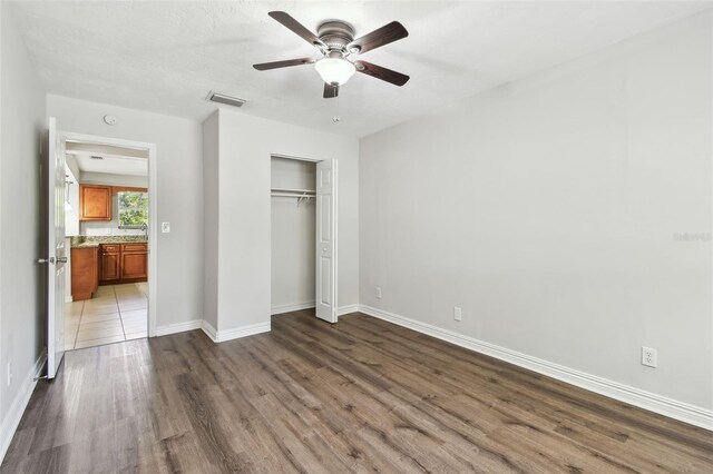 5010 8th Ave N, Saint Petersburg, FL 33710 - unfurnished bedroom featuring wood finished floors, a closet, baseboards, and a ceiling fan