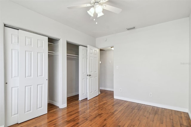 5010 8th Ave N, Saint Petersburg, FL 33710 - unfurnished bedroom featuring two closets, baseboards, wood finished floors, and ceiling fan