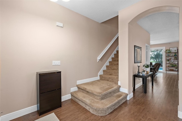 460 Tess Ct, Orlando, FL 32824 - stairway featuring arched walkways, wood finished floors, baseboards, and a textured ceiling